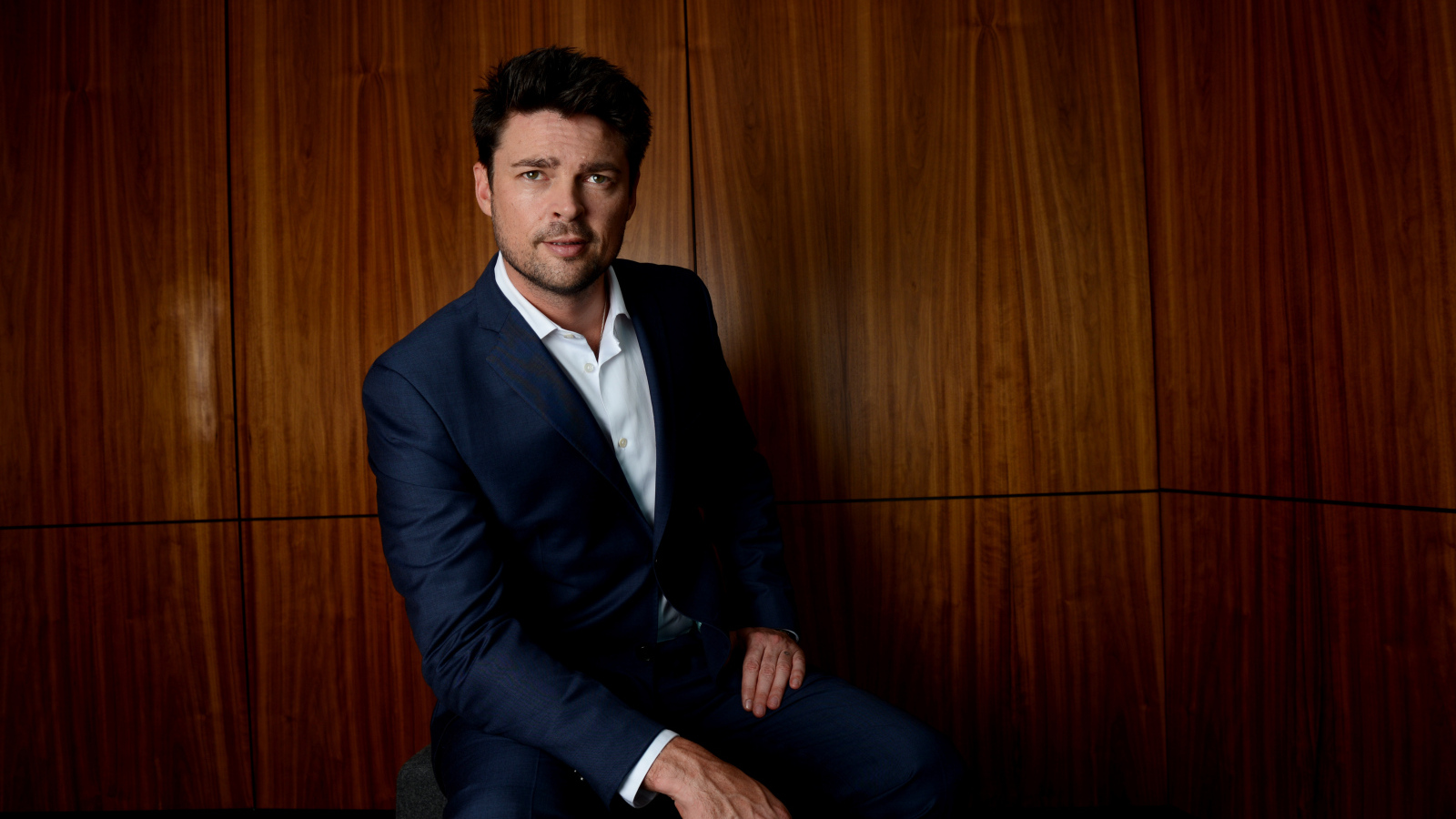 Актер Карл Урбан в костюме на фоне стены