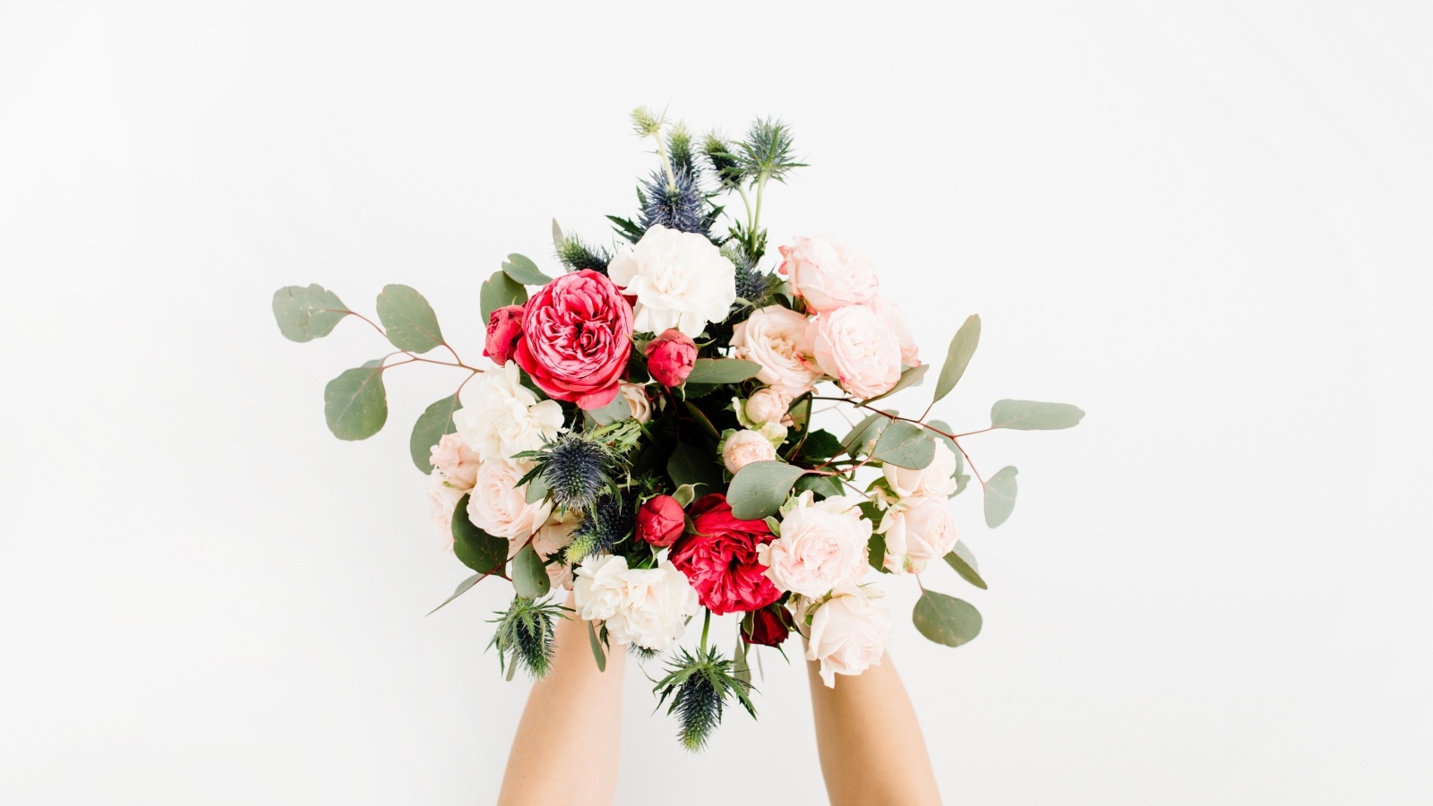 Букет цветов в руках у девушки на сером фоне