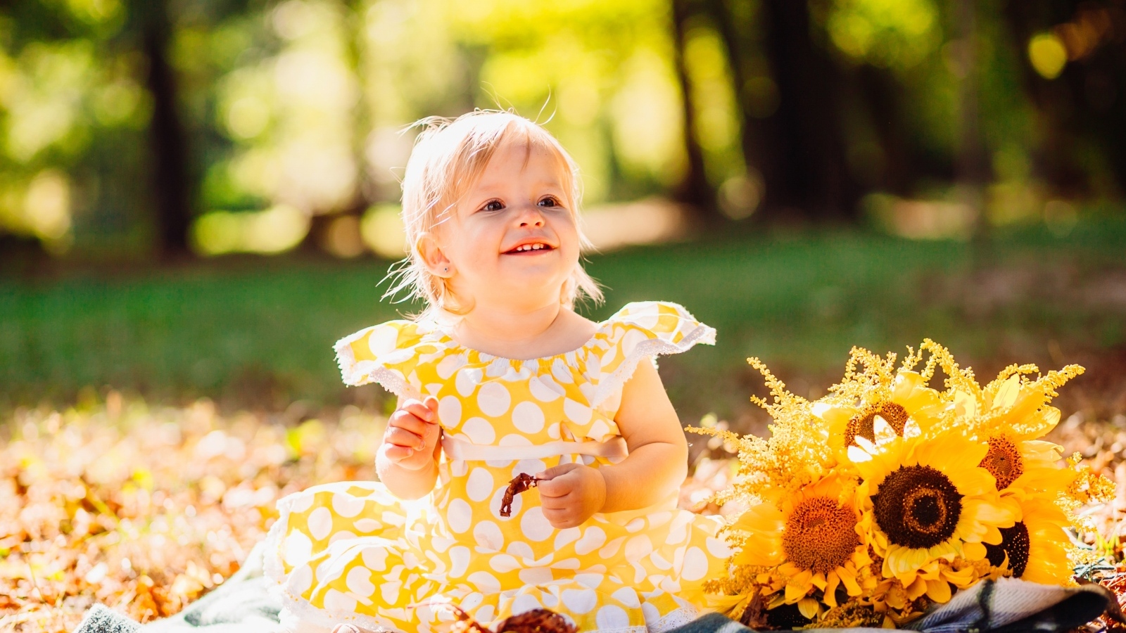 Малышка с цветами подсолнуха на траве