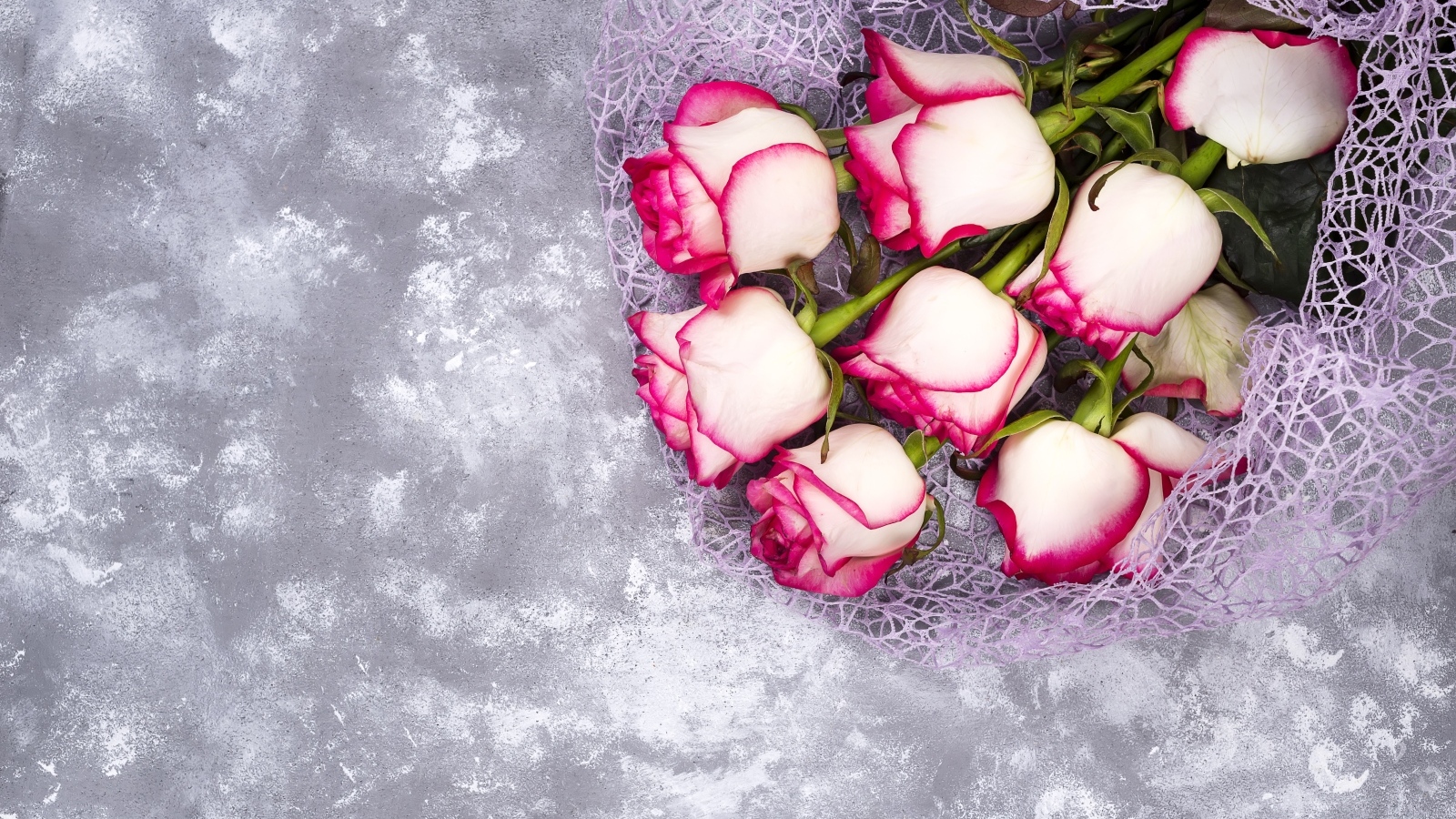 Красивый букет роз в упаковке на сером столе