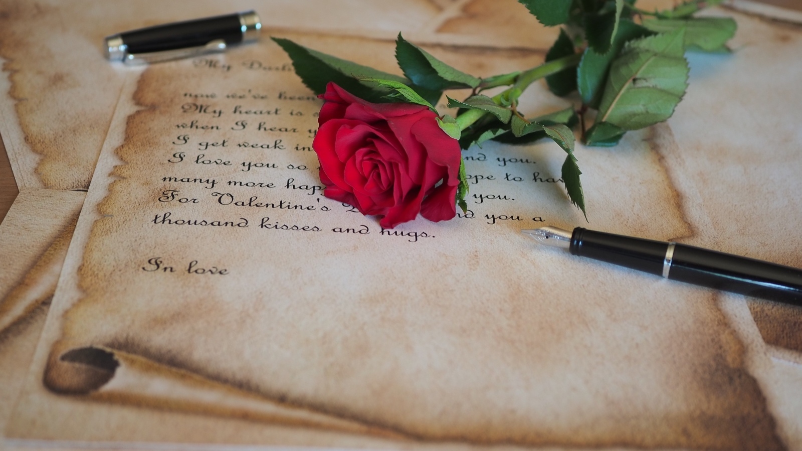 Красная роза с запиской и ручкой на столе
