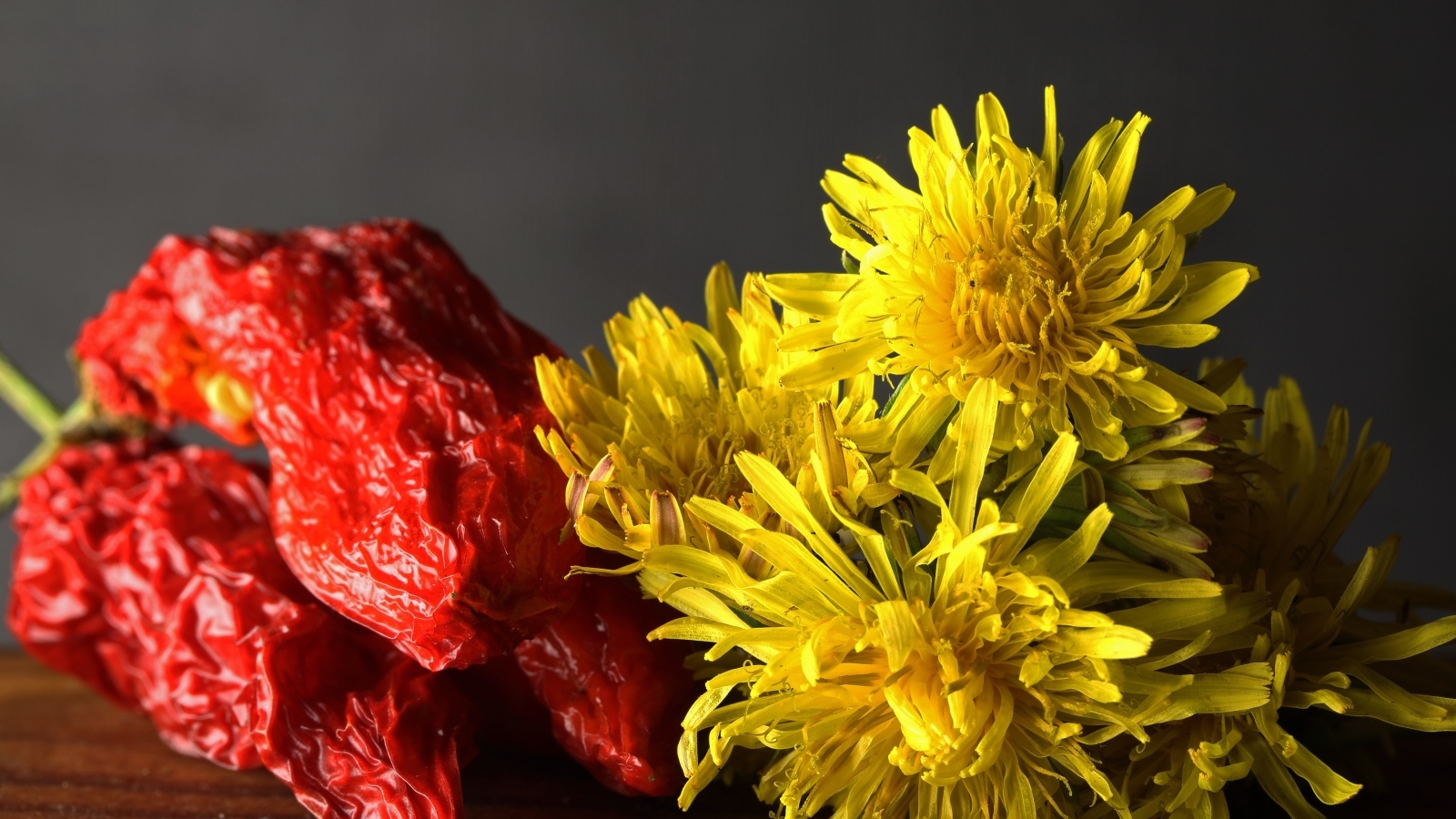 Желтые одуванчики с красным перцем на столе