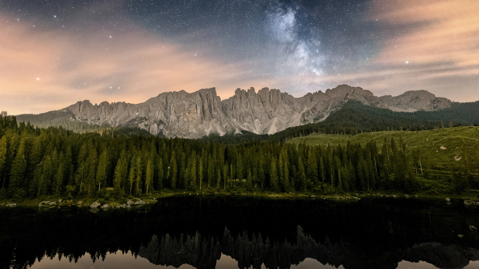 Млечный путь над горами и лесом отражающимися в воде