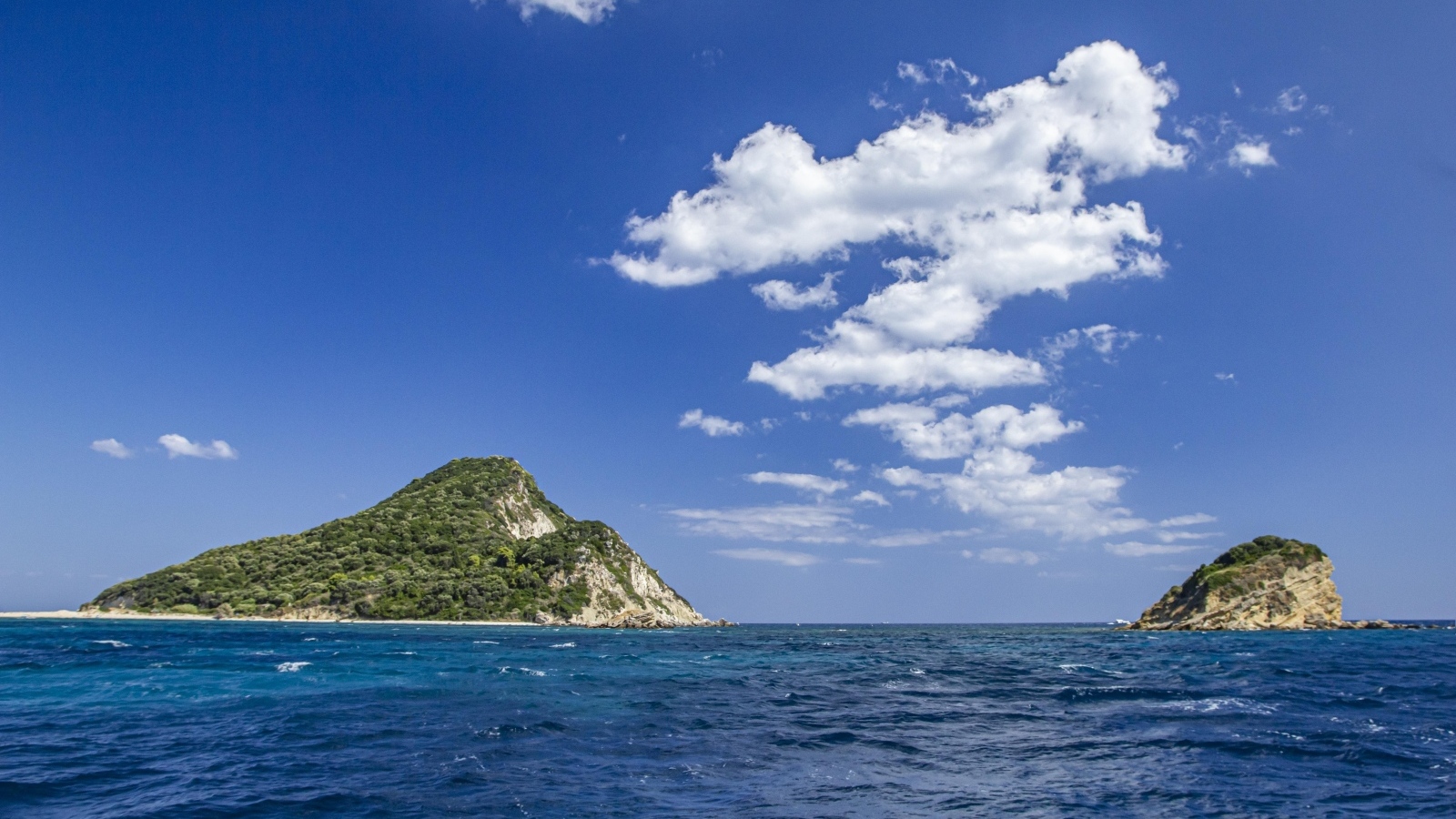 Покрытые зеленью горы в море под голубым небом