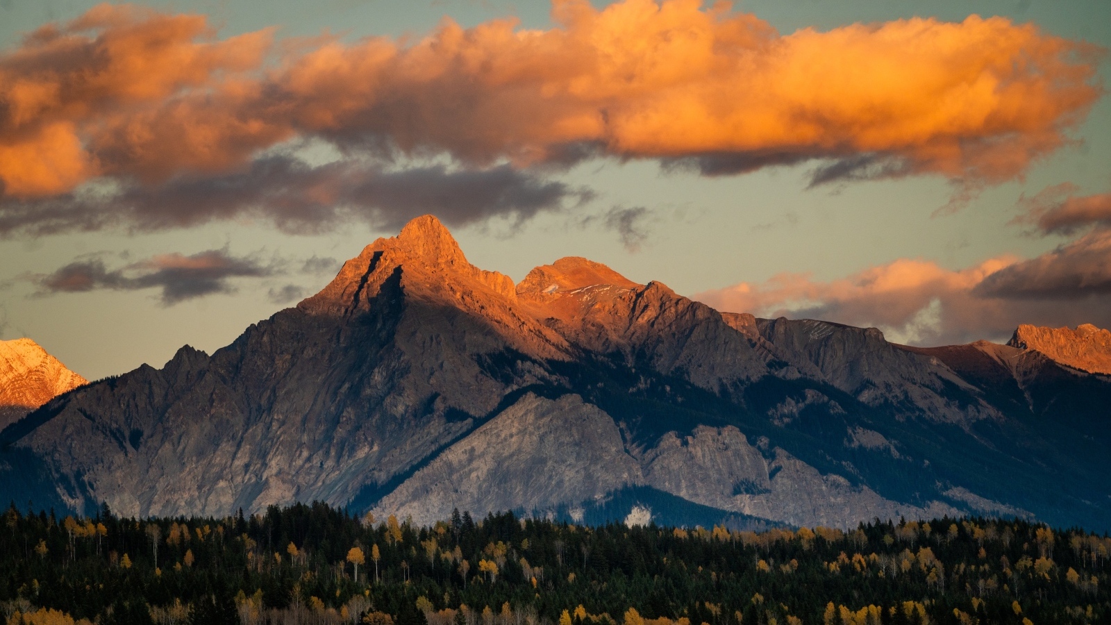 Солнце в облаках освещает вершину горы