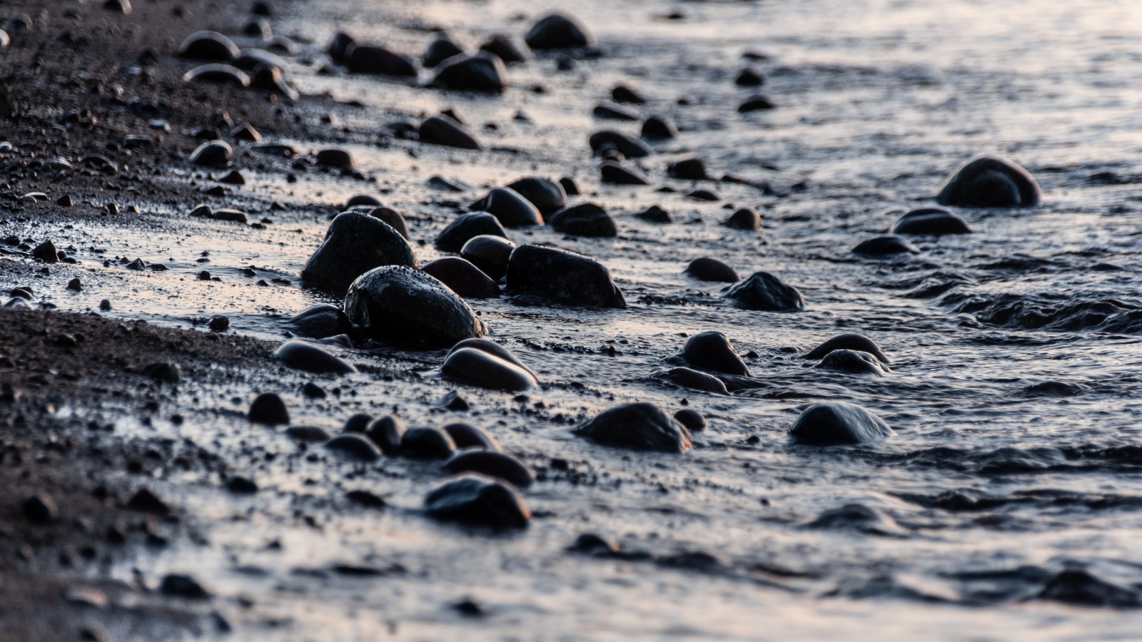 Мокрые камни на песке у моря