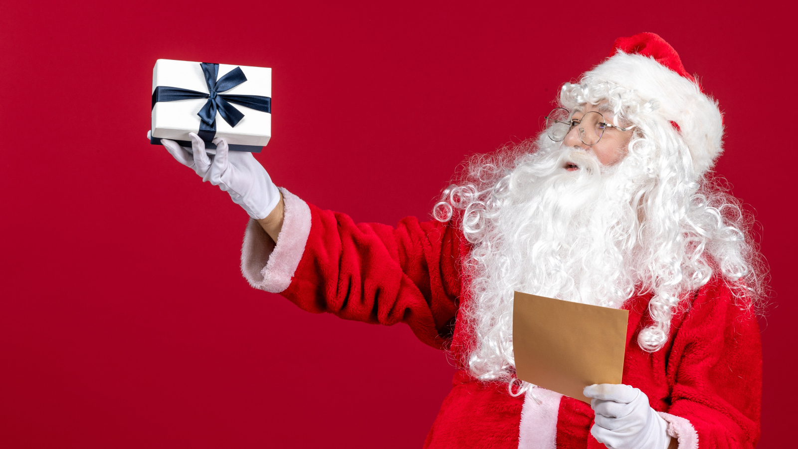 Санта Клаус с письмом на красном фоне