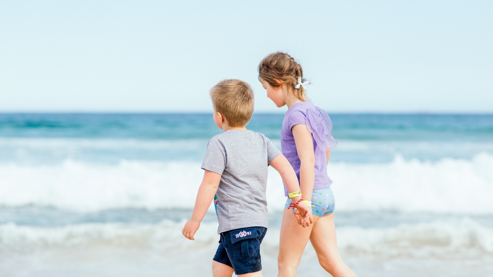 Мальчик и девочка идут по песку у моря