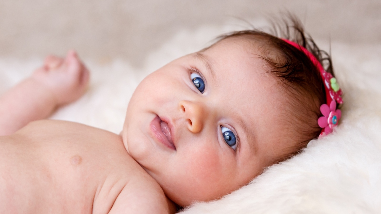 Голубоглазая новорожденная малышка с цветком на голове