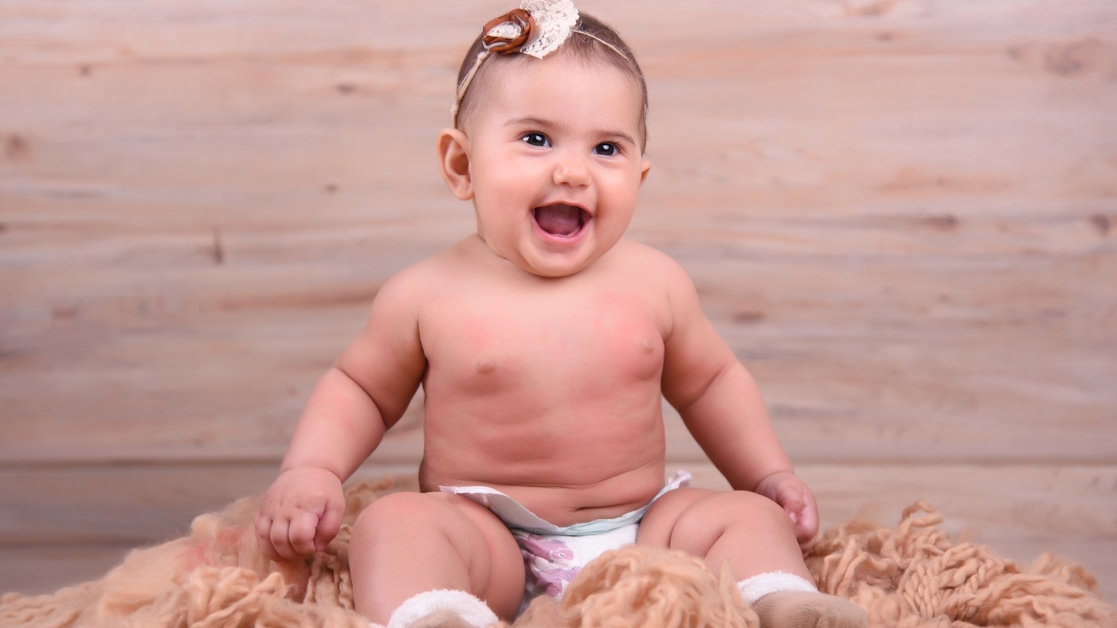 Милый улыбающийся ребенок на фоне деревянной стены