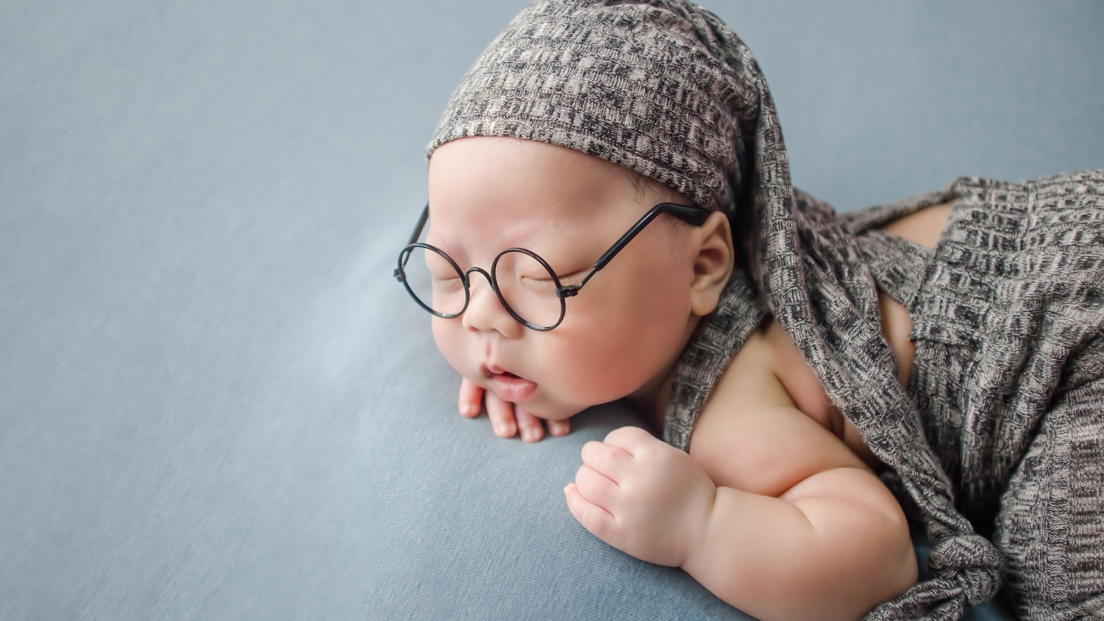 Забавный малыш в очках одет в серый костюм