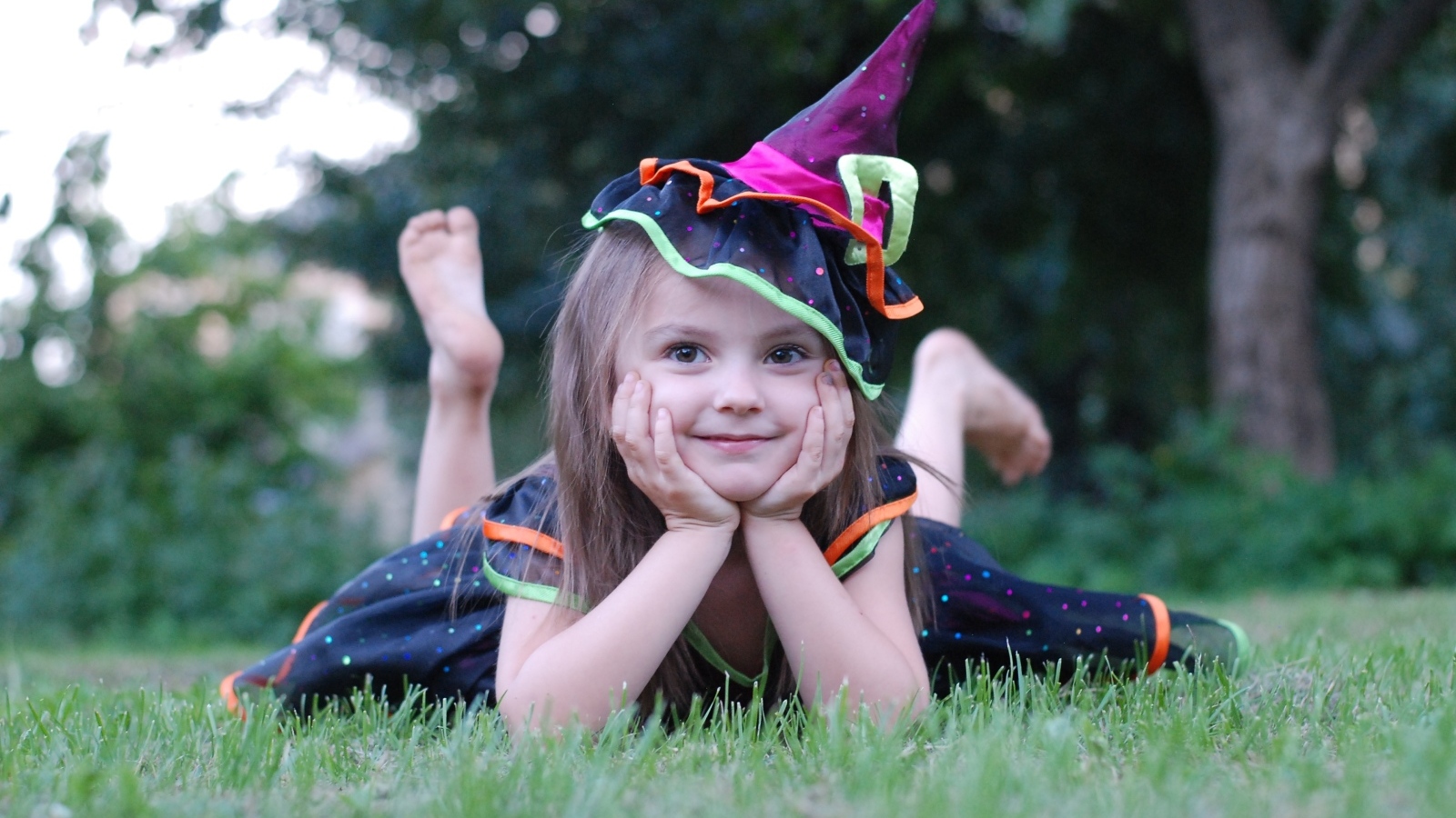 Девочка в костюме лежит на зеленой траве