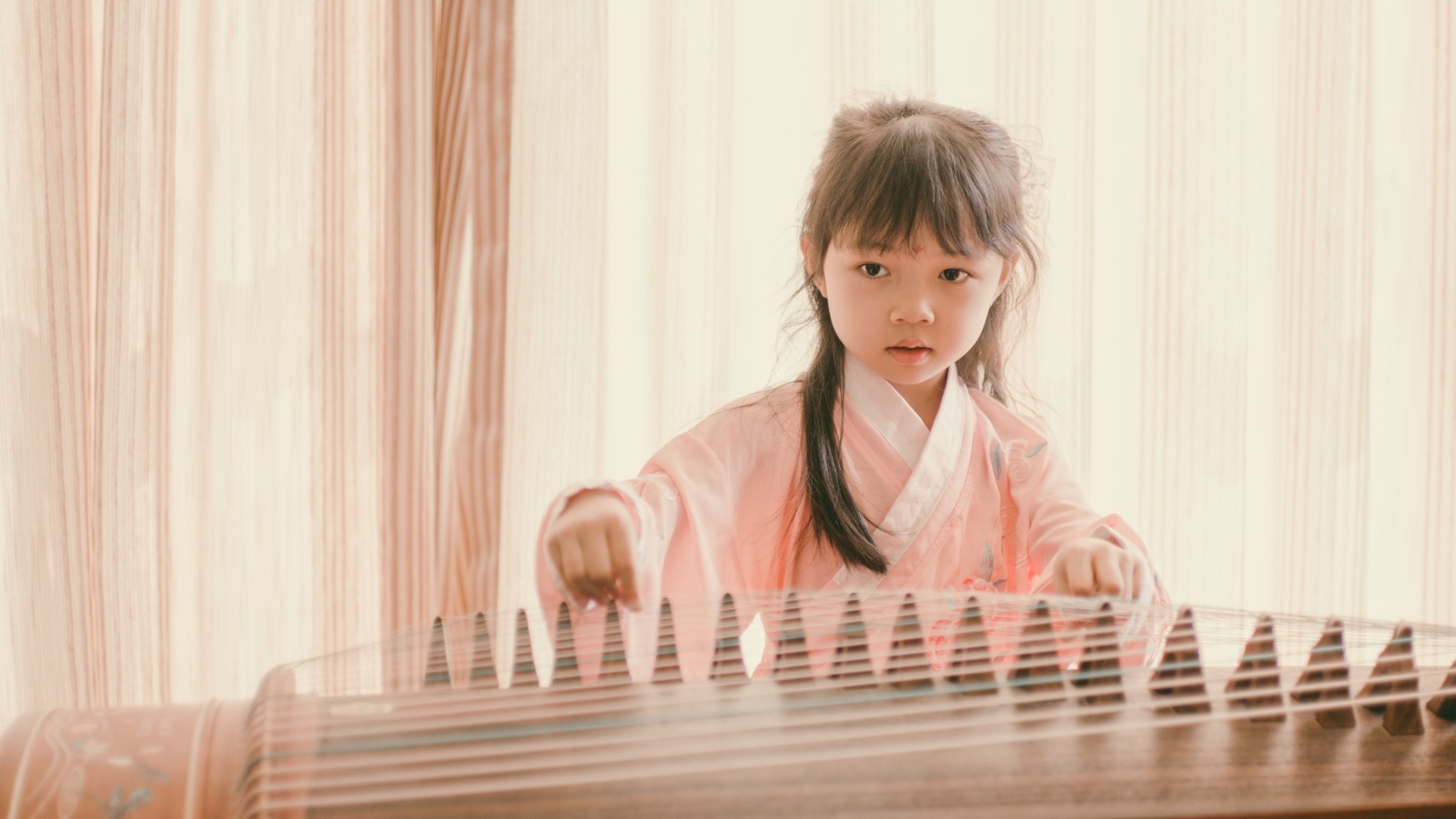 Маленькая девочка азиатка играет на музыкальном инструменте