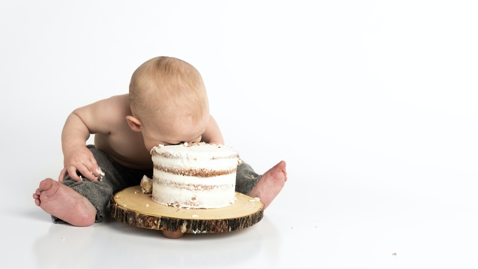 Маленький мальчик ест праздничный торт на белом фоне