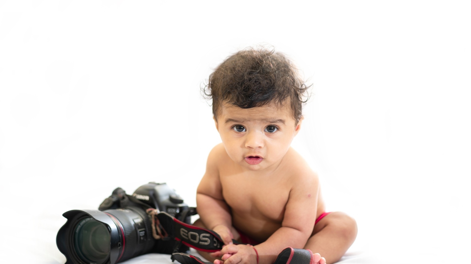 Маленький мальчик с фотоаппаратом на белом фоне