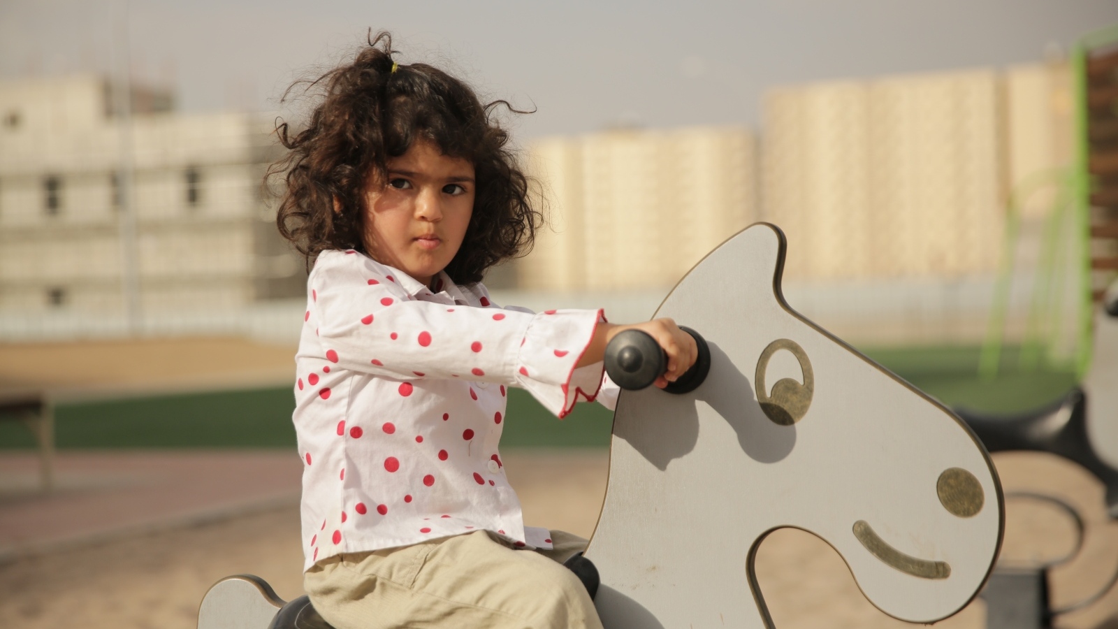 Маленькая девочка на деревянной лошади