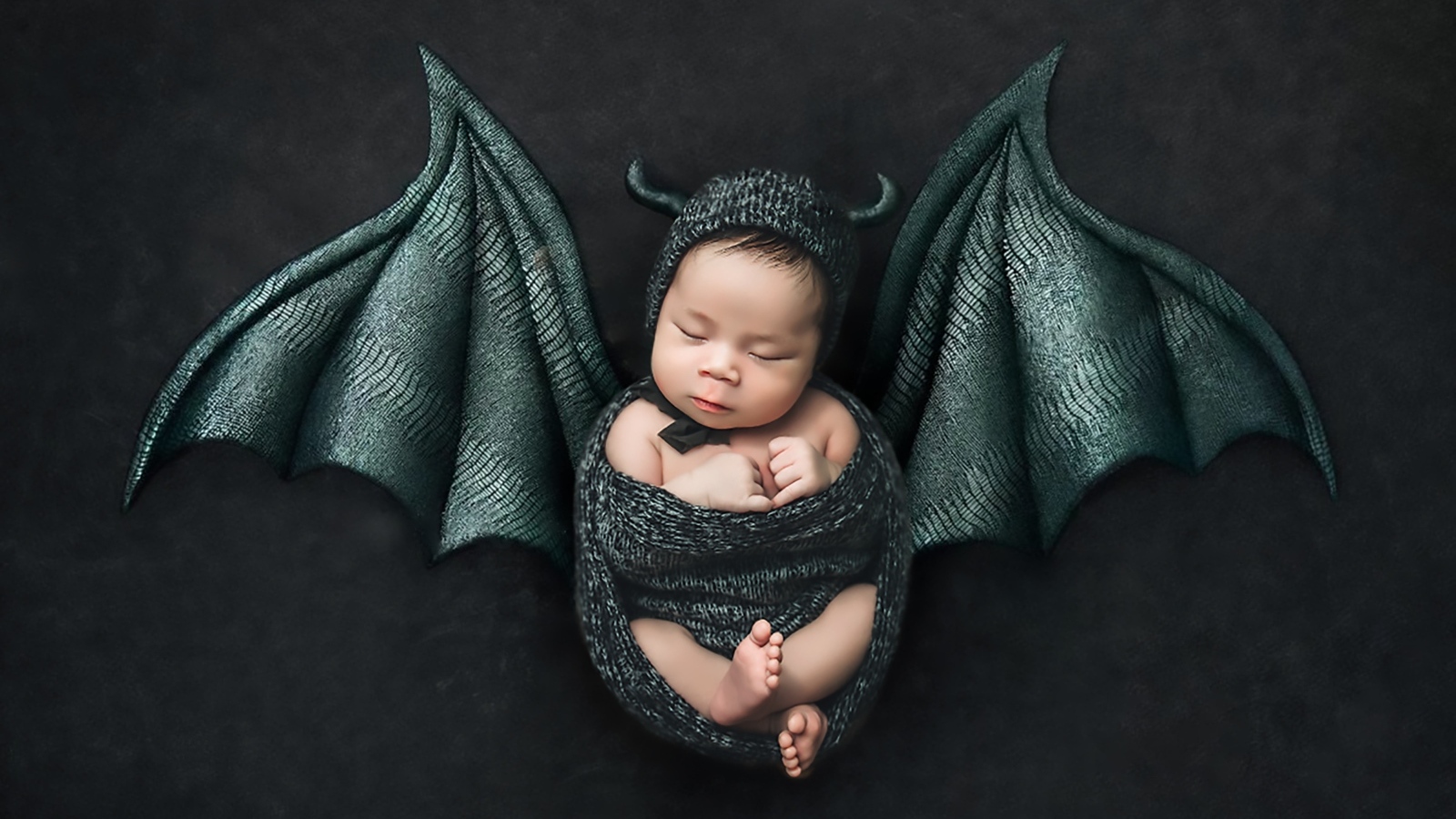 Маленький спящий ребенок с крыльями на Хэллоуин