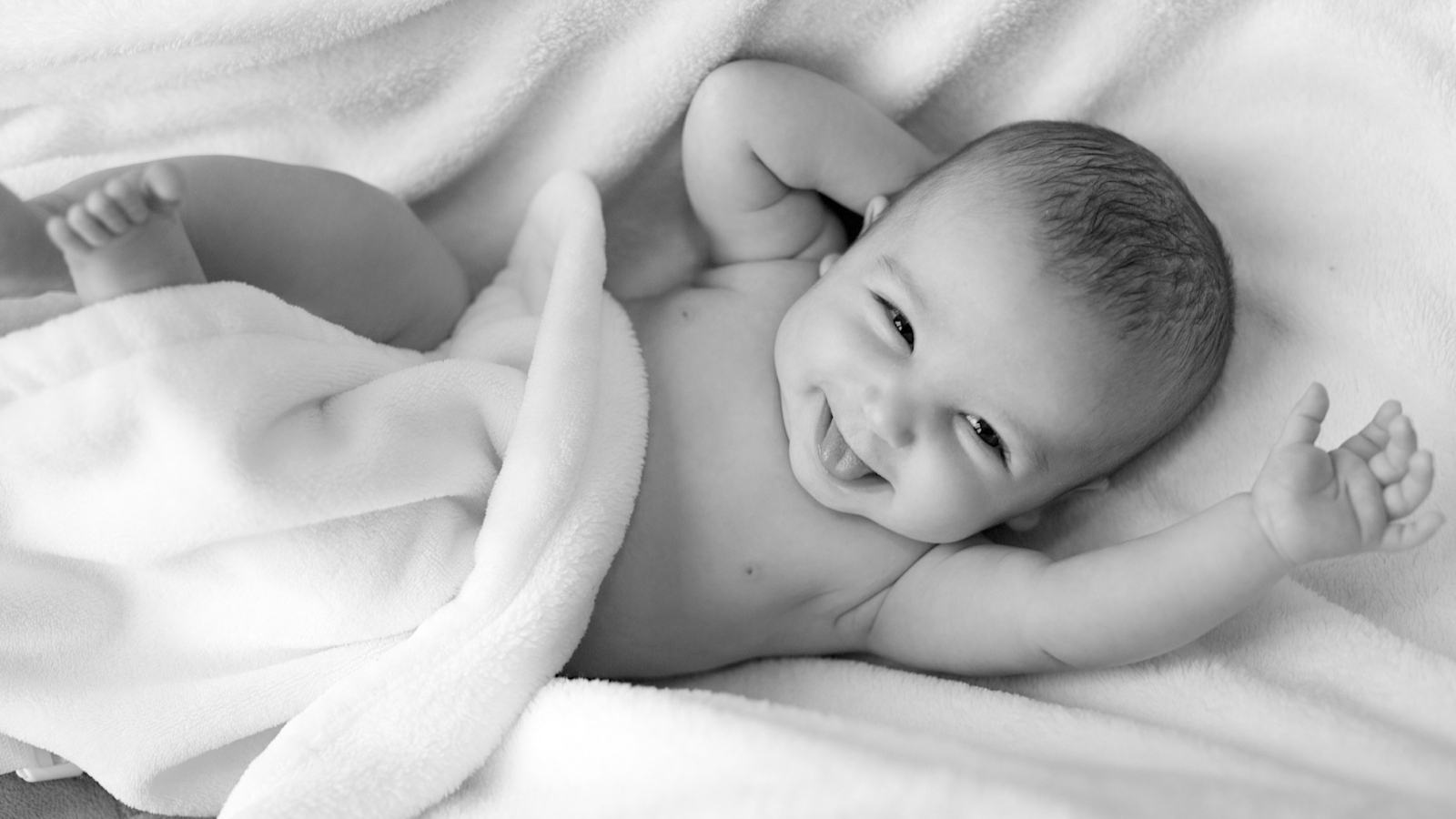 Маленький улыбающийся ребенок в белом покрывале