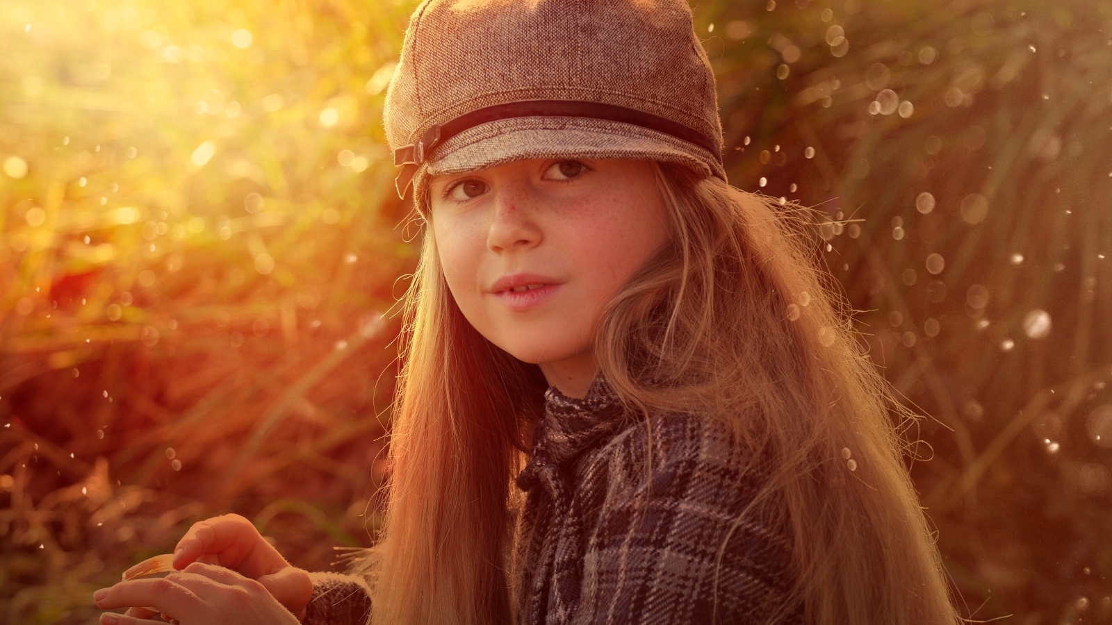 Длинноволосая девочка в кепке в лучах солнца