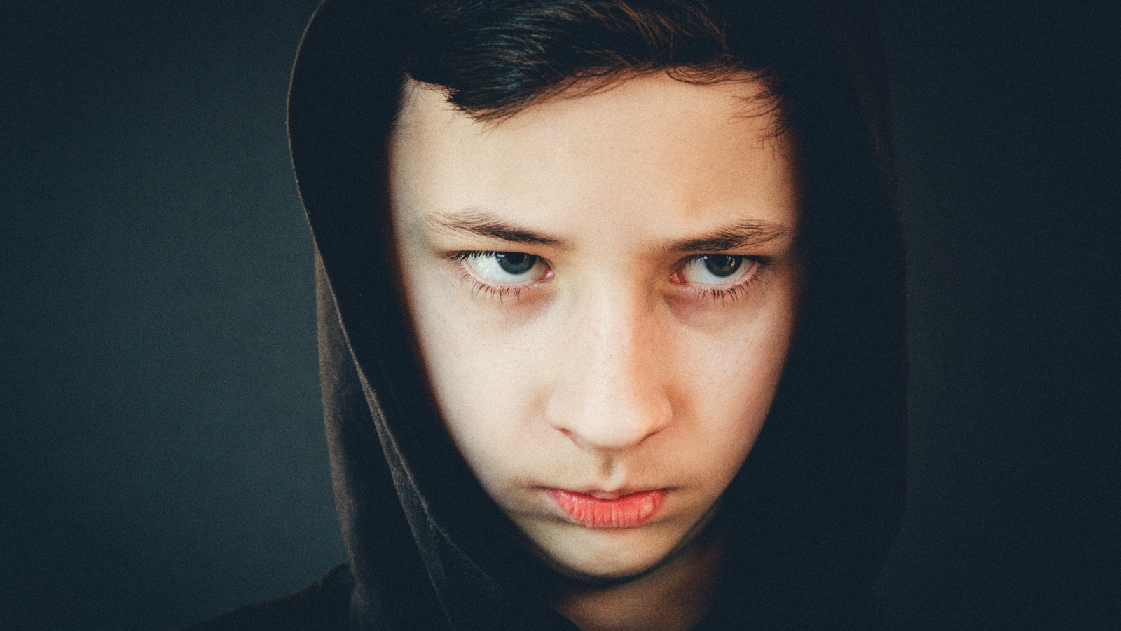 Серьезный мальчик в черном капюшоне