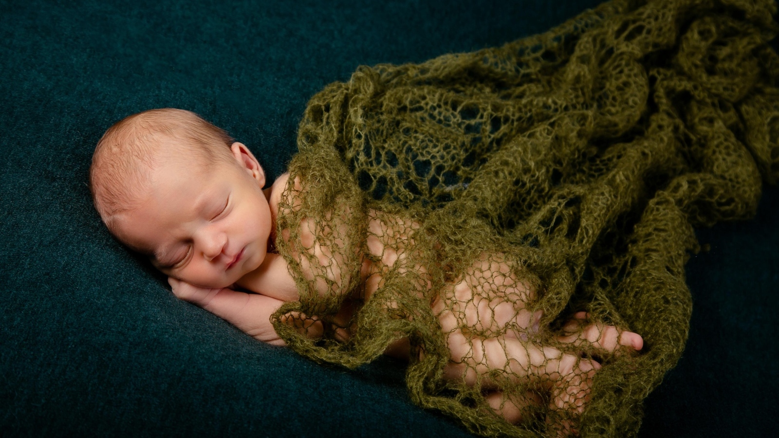 Спящий новорожденный ребенок укрыт шалью