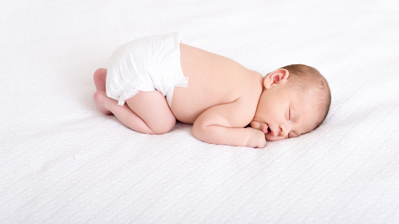Спящий новорожденный ребенок в памперсе