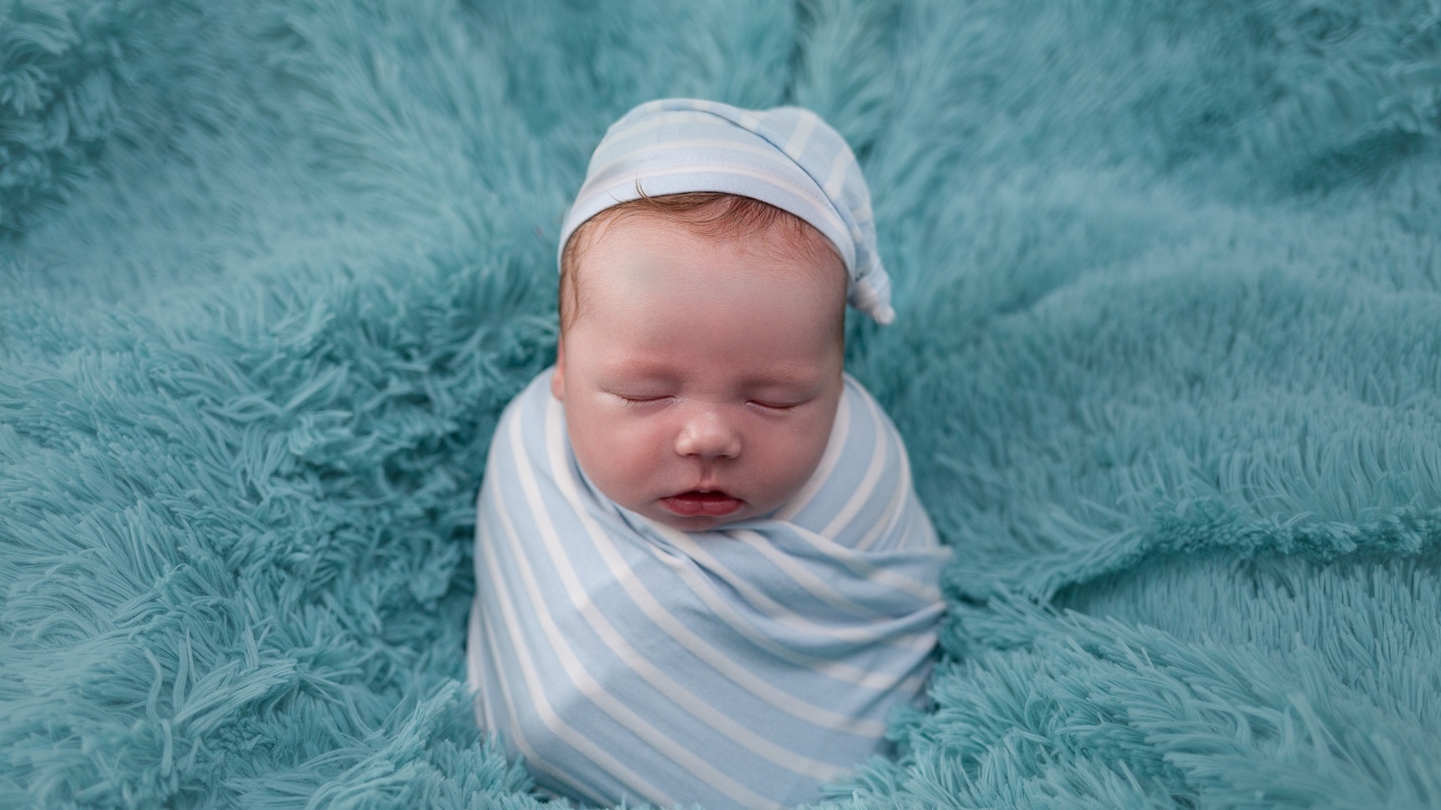 Спящий новорожденный малыш на голубом покрывале 
