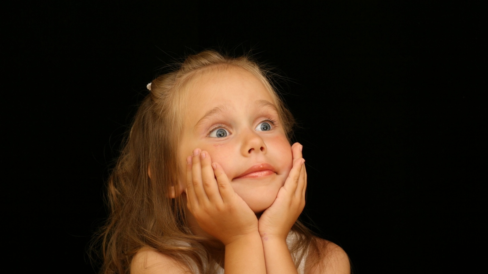 Удивленная маленькая девочка на черном фоне