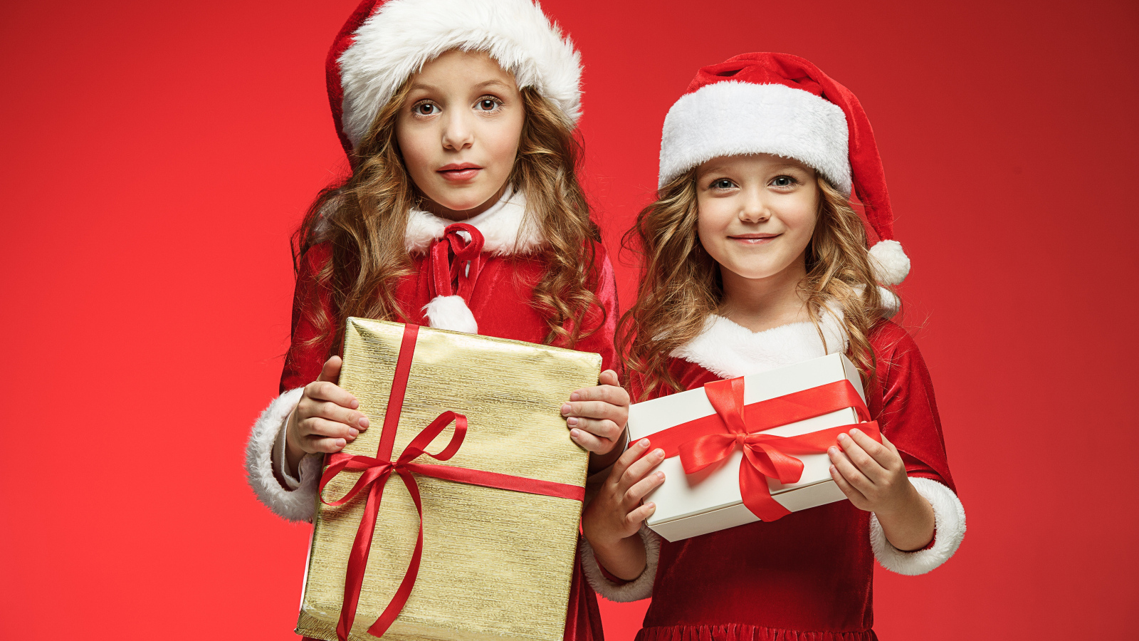 Две маленькие девочки в новогодних костюмах с подарками