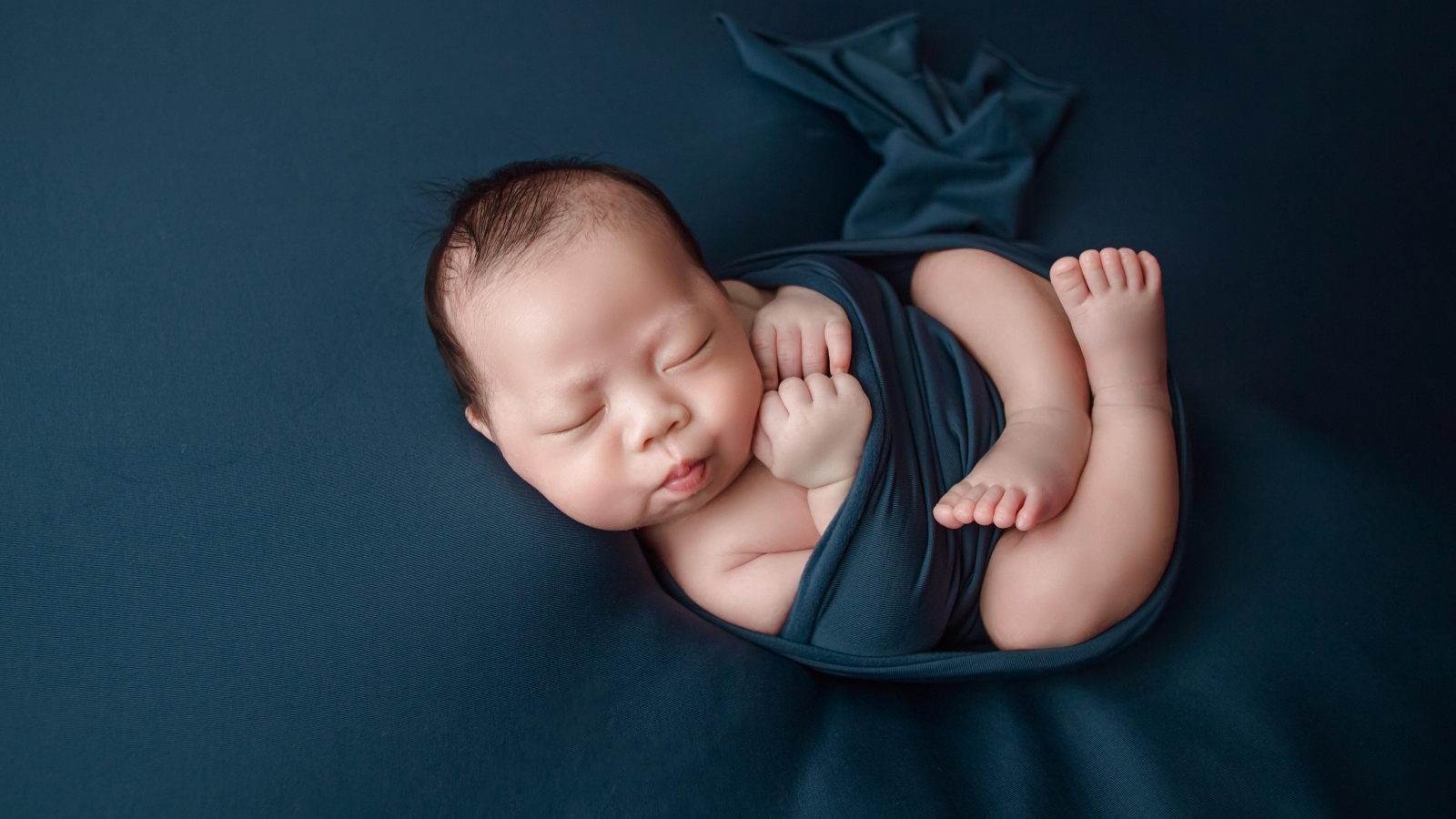 Новорожденный малыш в черном покрывале