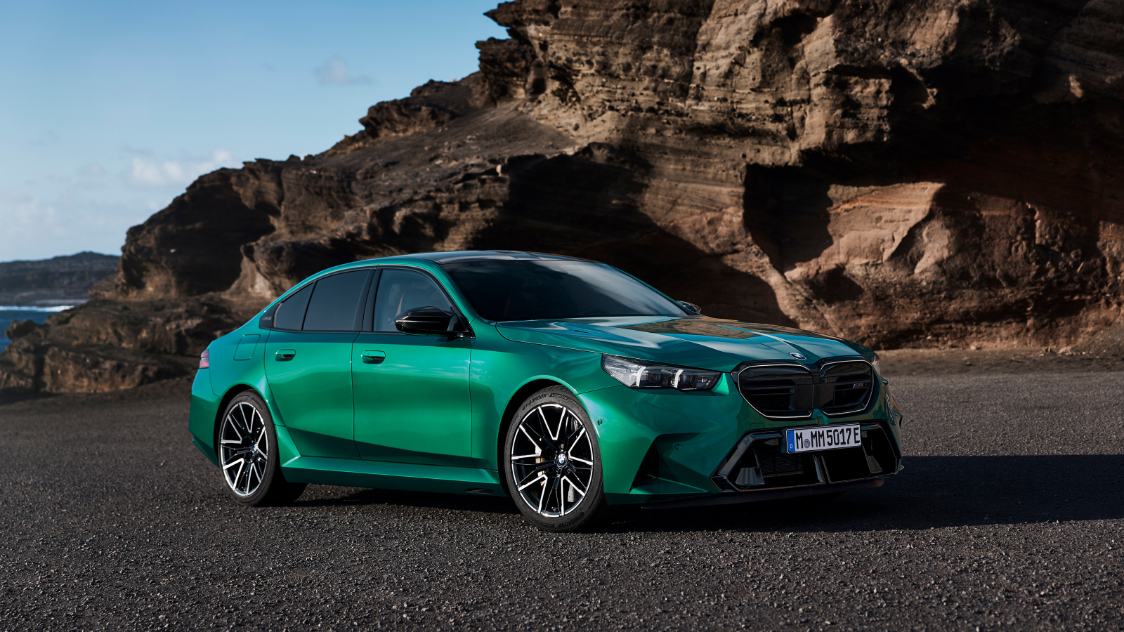 Зеленый автомобиль BMW M5 2024 года на фоне гор