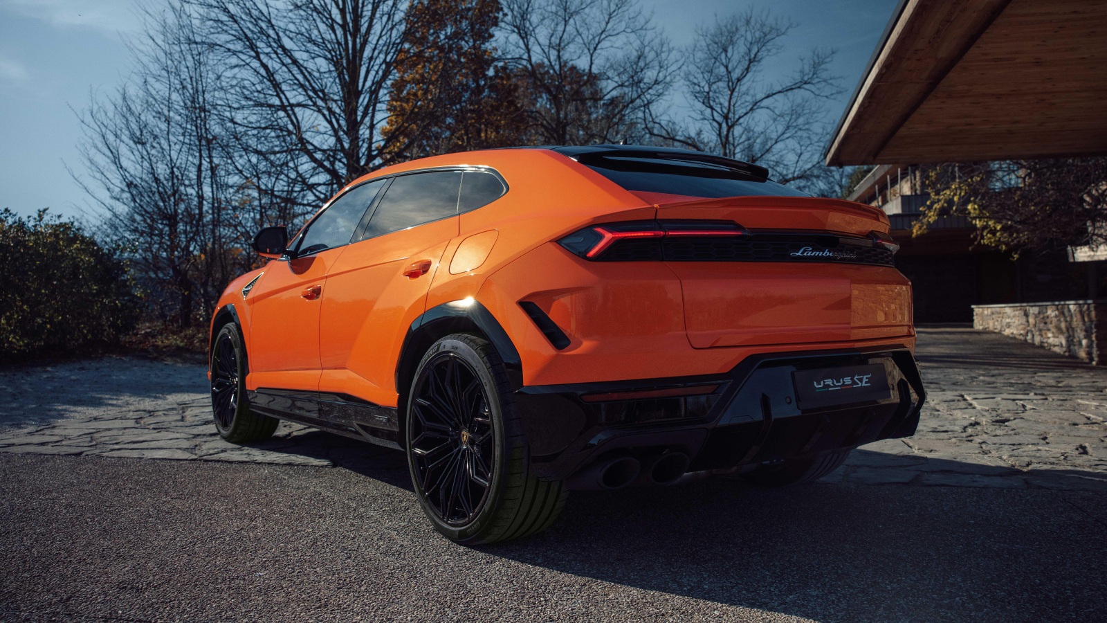 Вид сзади на оранжевый внедорожник Lamborghini Urus SE Plug-In Hybrid
