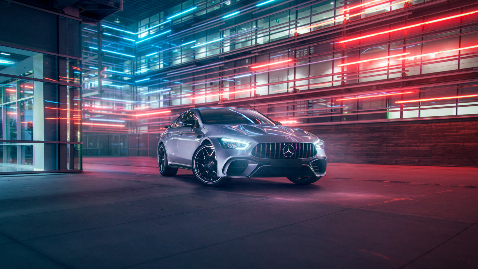 Серебристый автомобиль Mercedes AMG GT4 на фоне здания