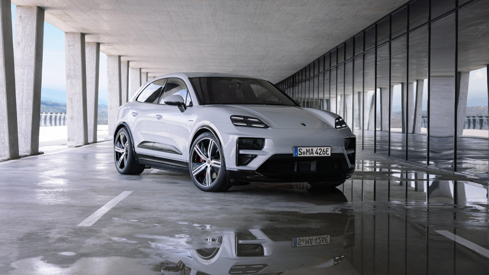 Большой Porsche Macan Turbo 2024 года у здания