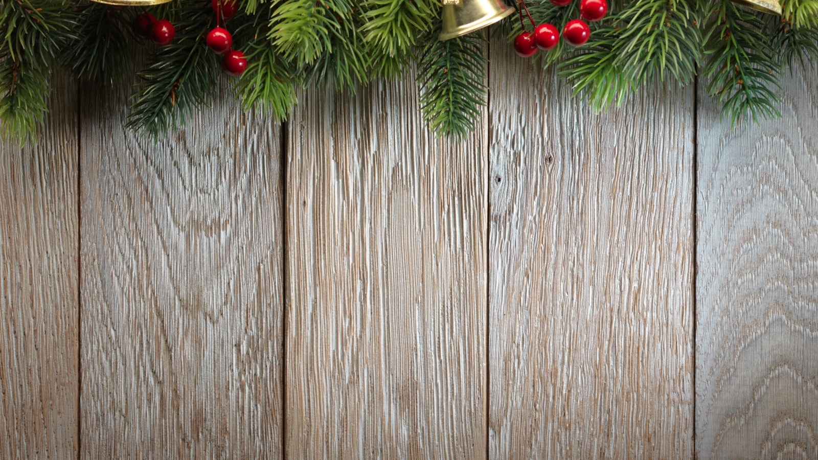 Деревянный новогодний фон с еловой веткой и колокольчиками
