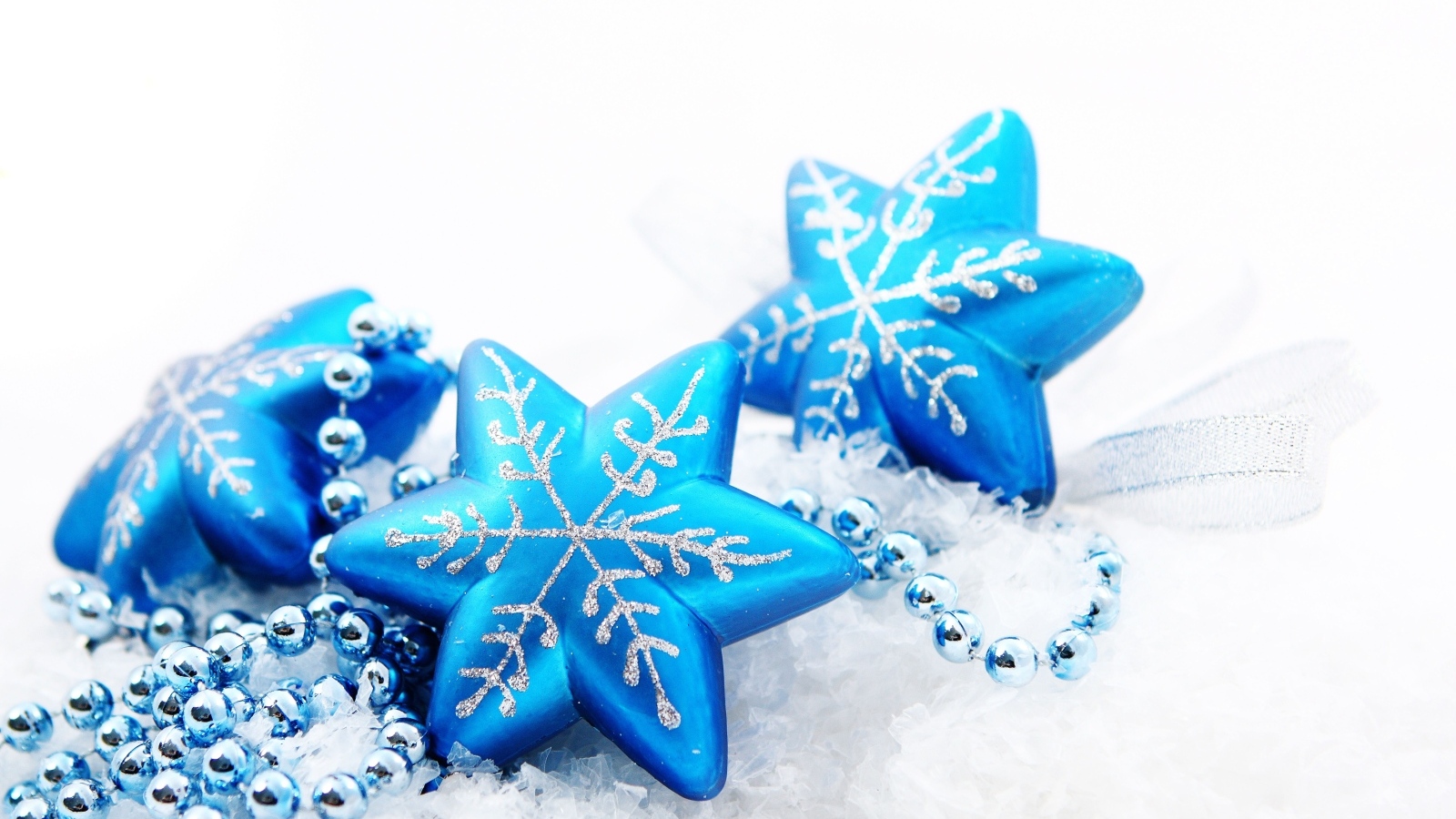 Синие снежинки с бусами на белом фоне на Рождество