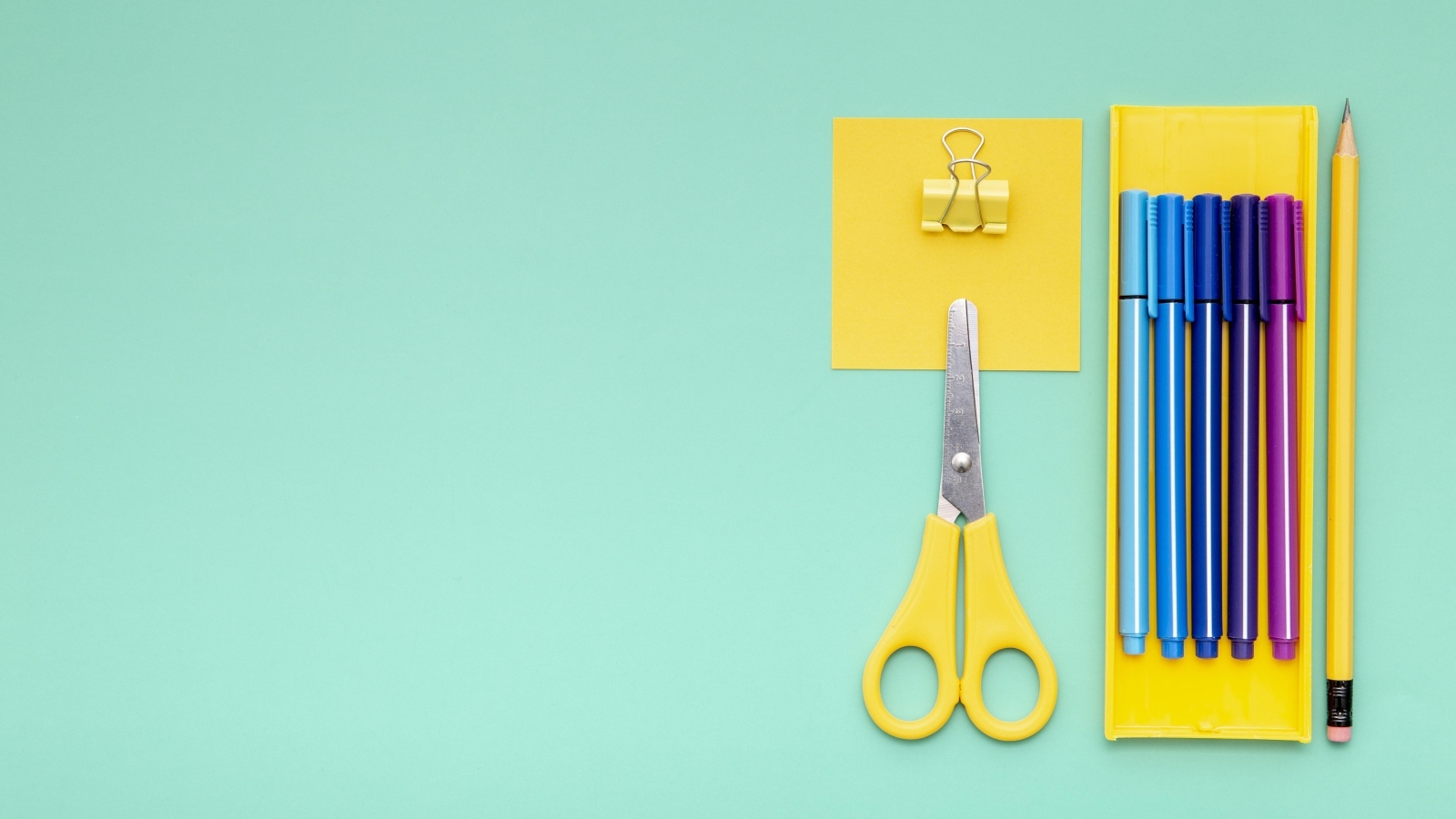 Фломастеры, ножницы и карандаш на голубом фоне