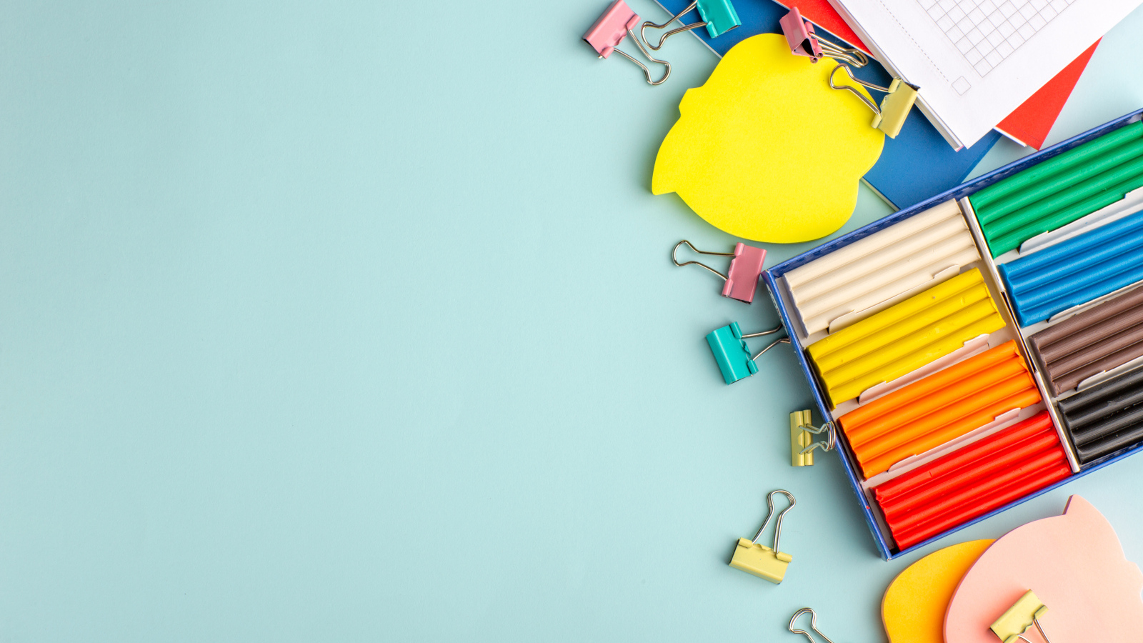 Пластилин на голубом фоне со скрепками и блокнотами