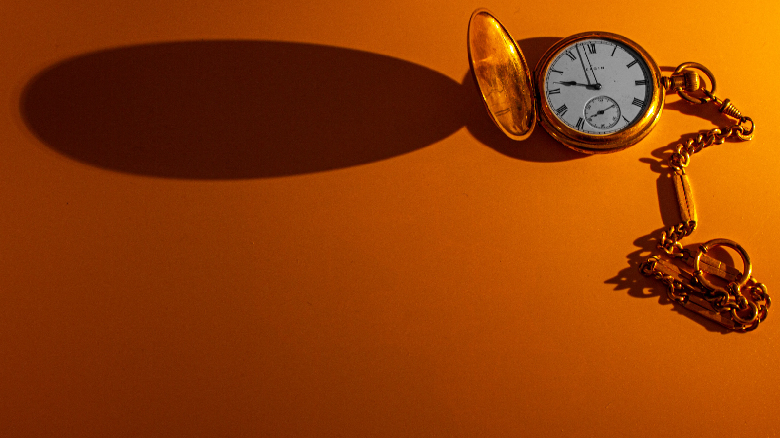 Тень от карманных часов на оранжевом фоне