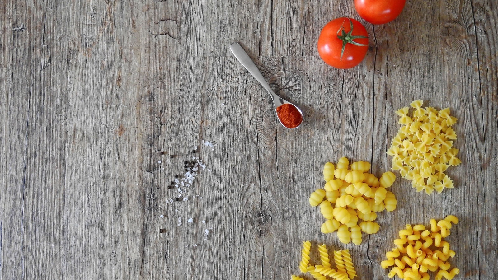 Разные виды макарон на столе с помидорами