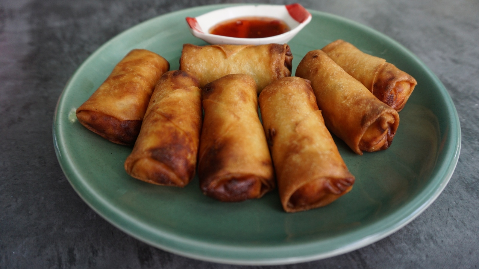 Яичные рулетики на большой тарелке с соусом