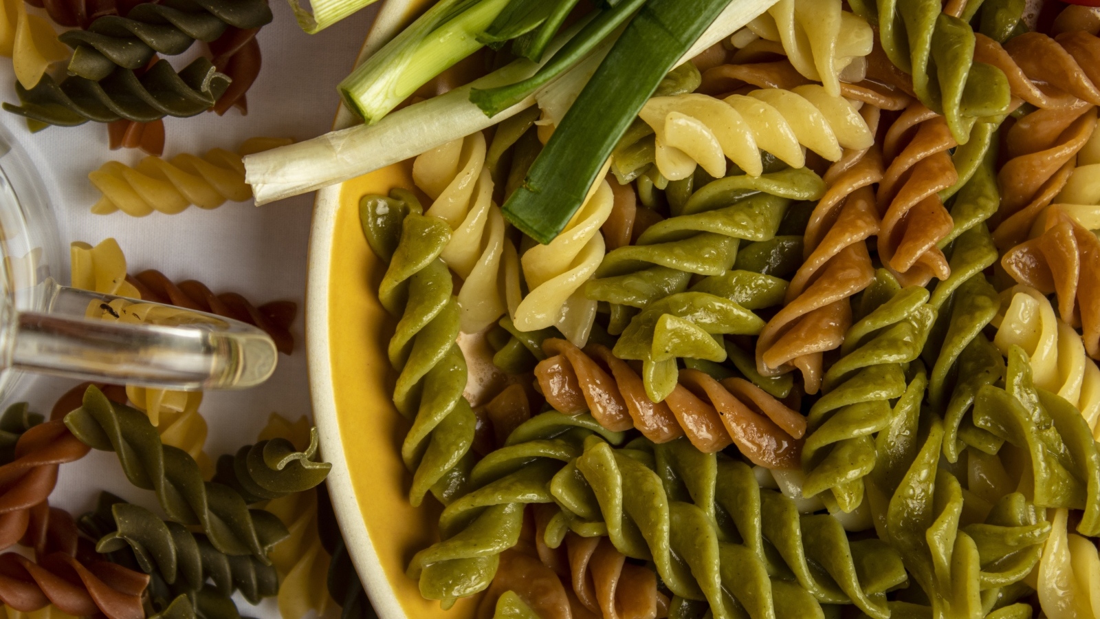 Разноцветные сваренные макароны с зеленым луком