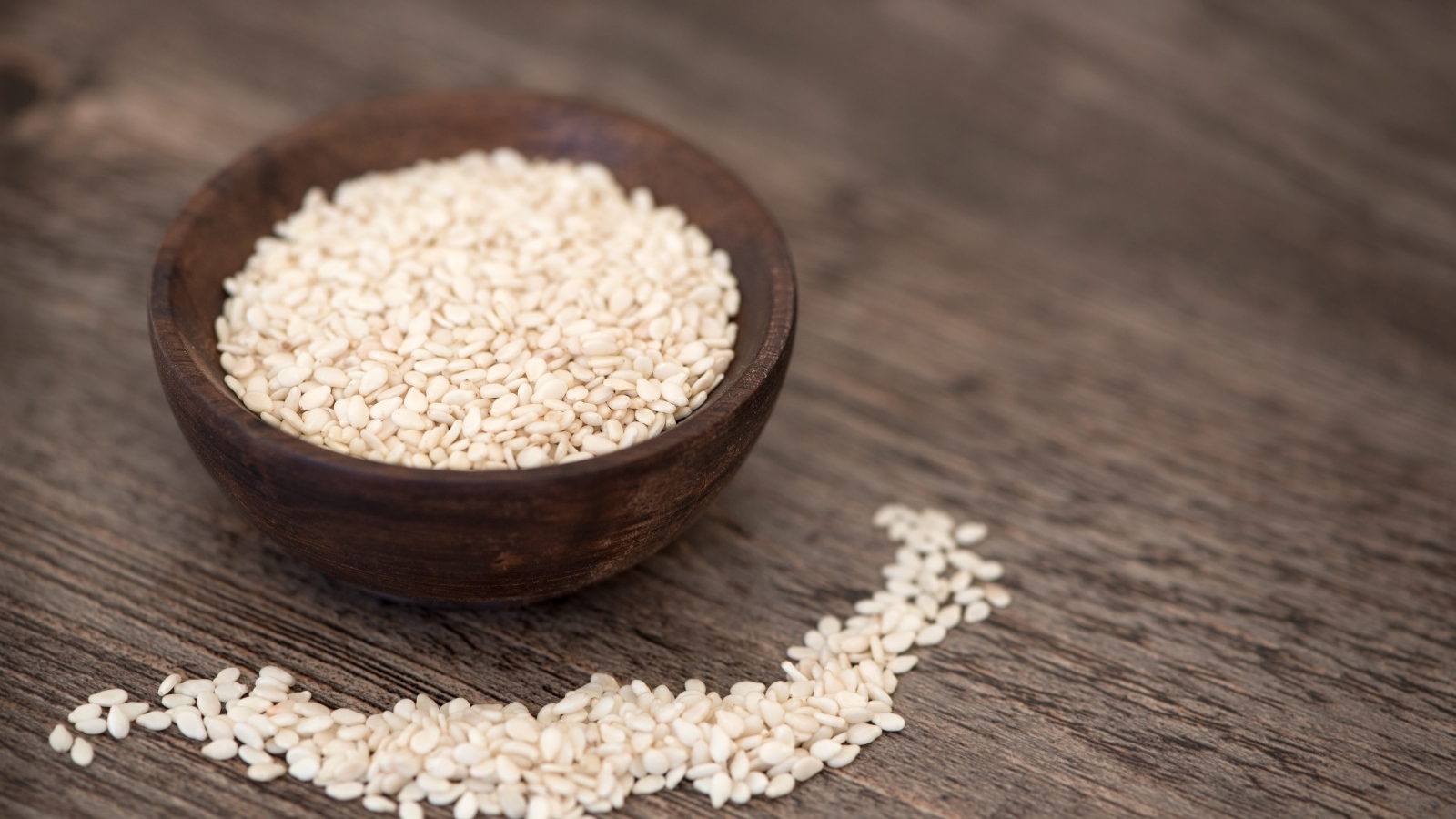 Зерна кунжута в деревянной миске на столе