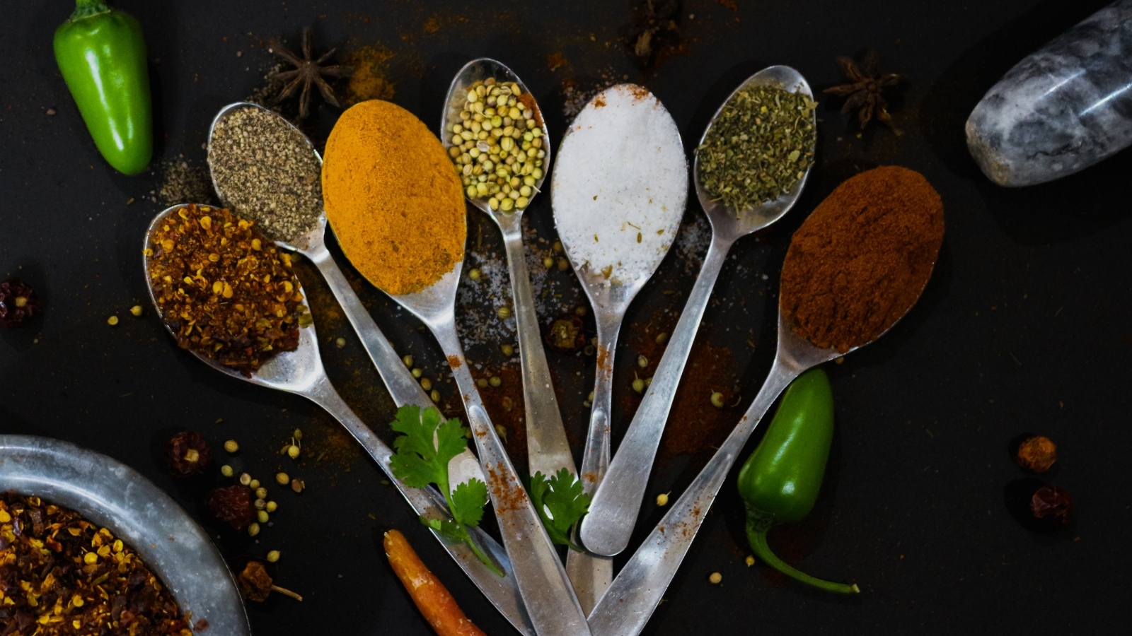 Ложки с ароматными специями на черном столе