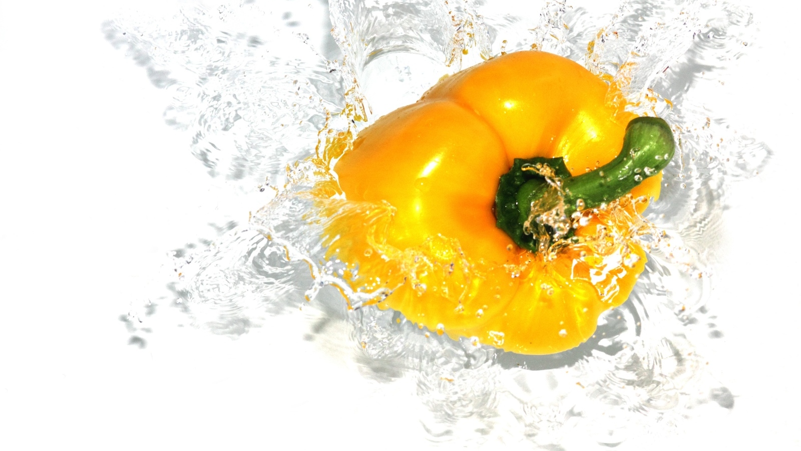 Желтый сладкий перец в воде на белом фоне