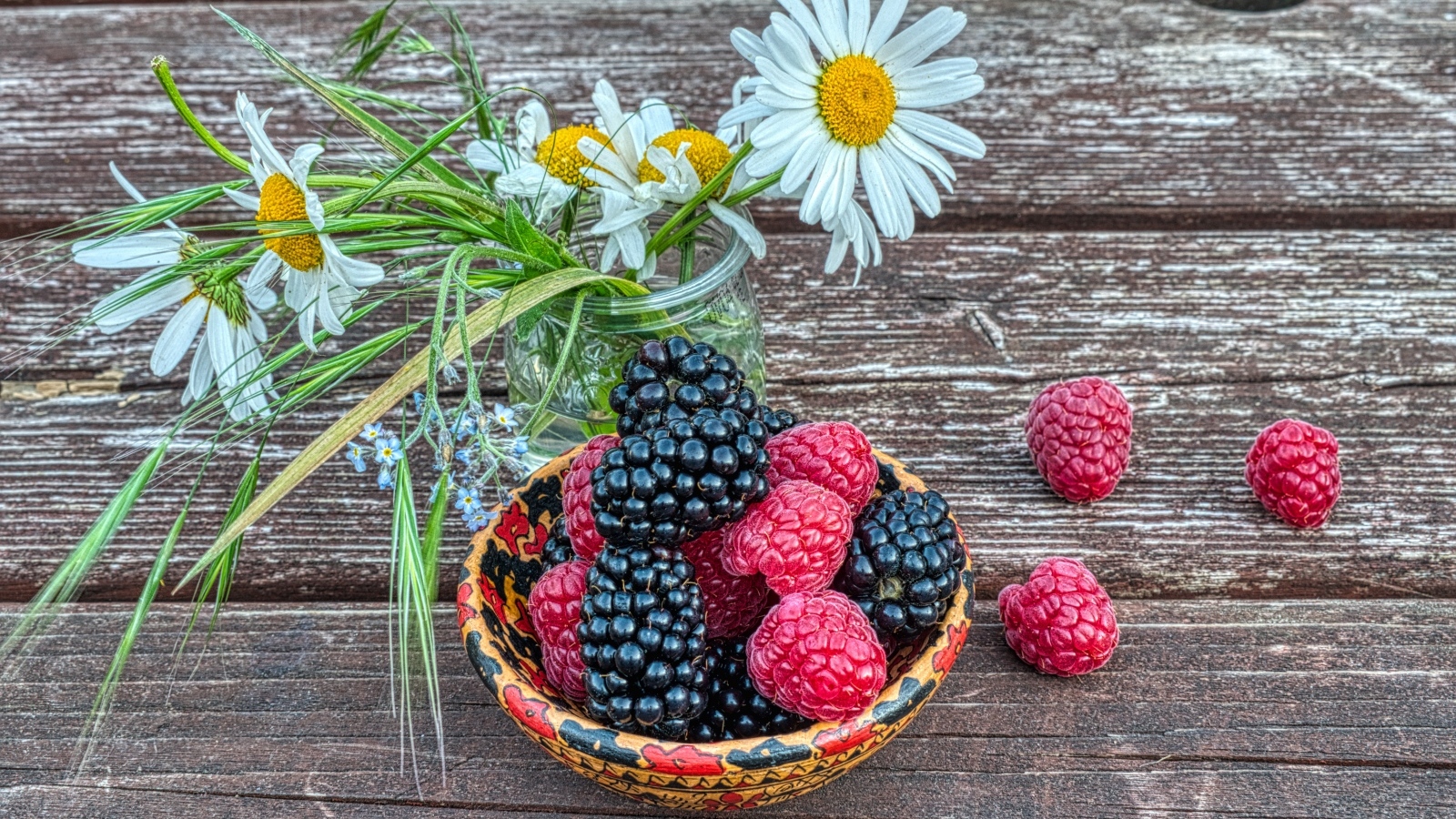 Ягоды черники и малины на столе с ромашками