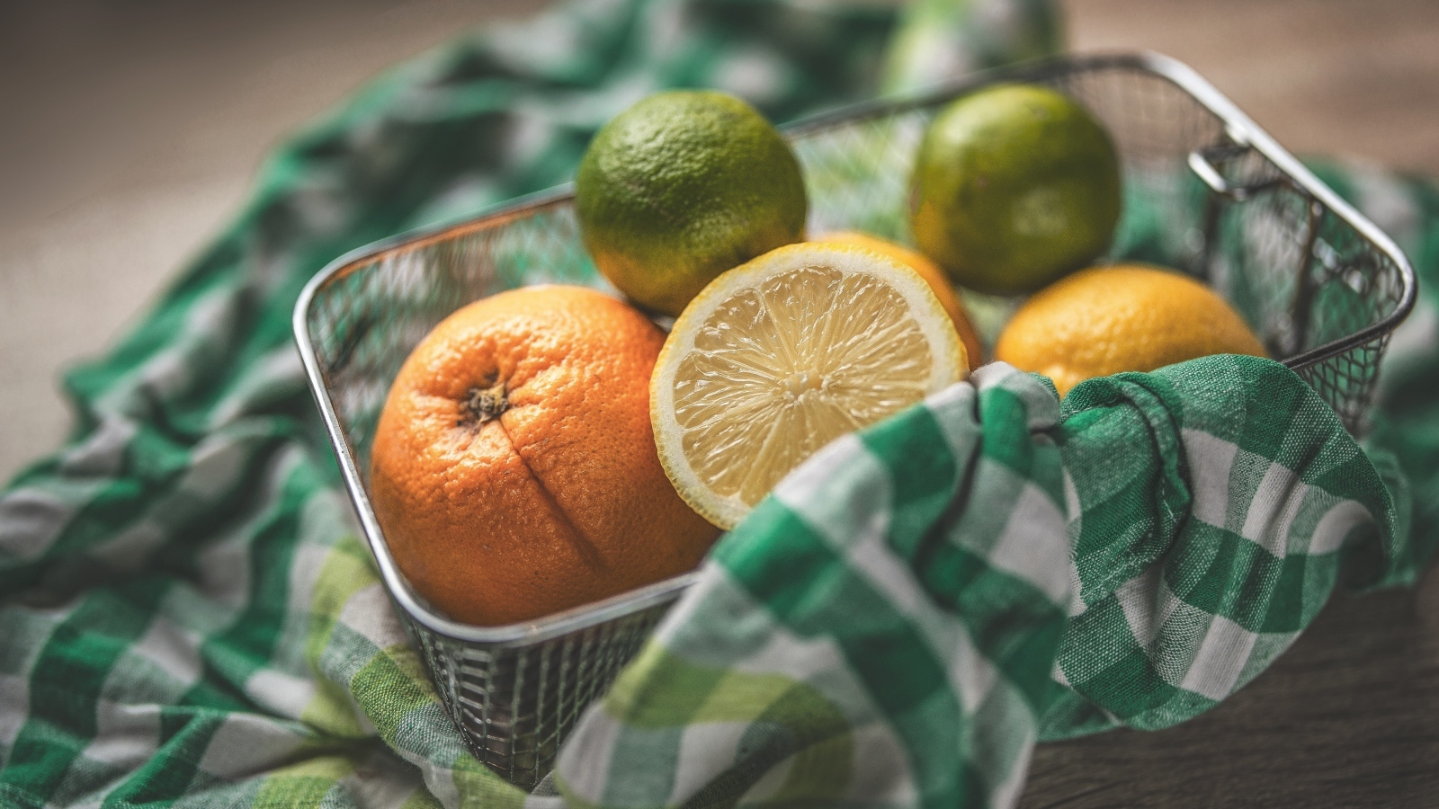 Цитрусовые фрукты в железной корзинке на столе