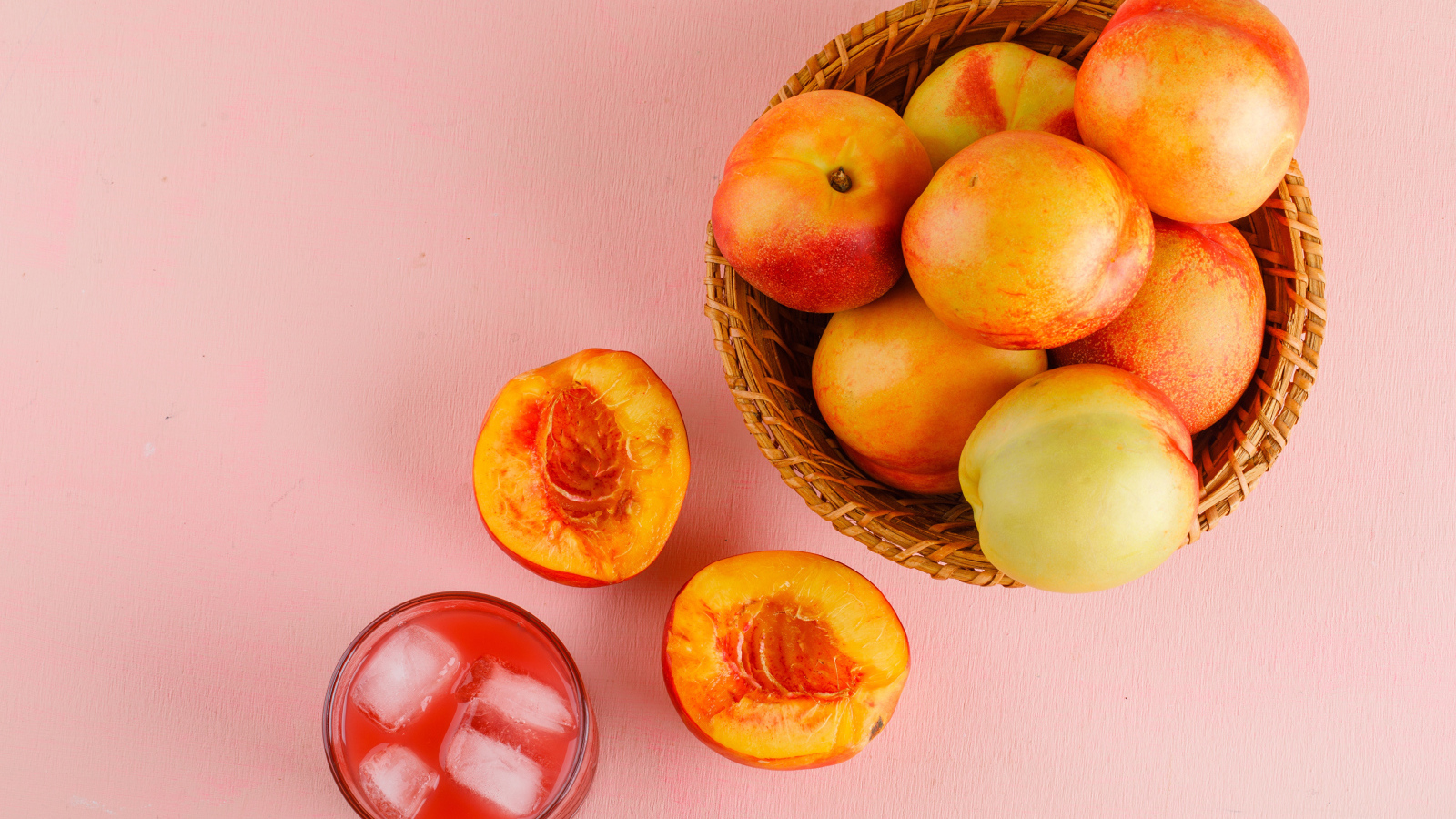 Свежий нектарин в корзине на розовом столе