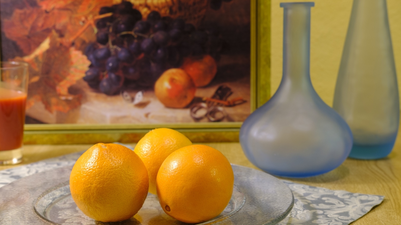 Три апельсина с вазами на столе