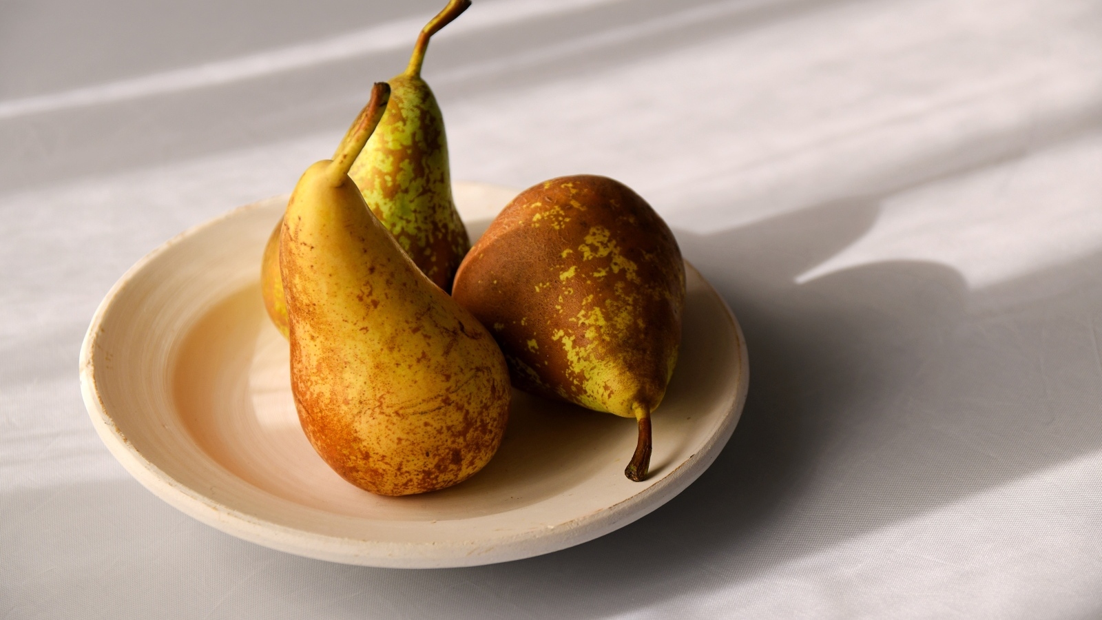 Три груши на тарелке на столе
